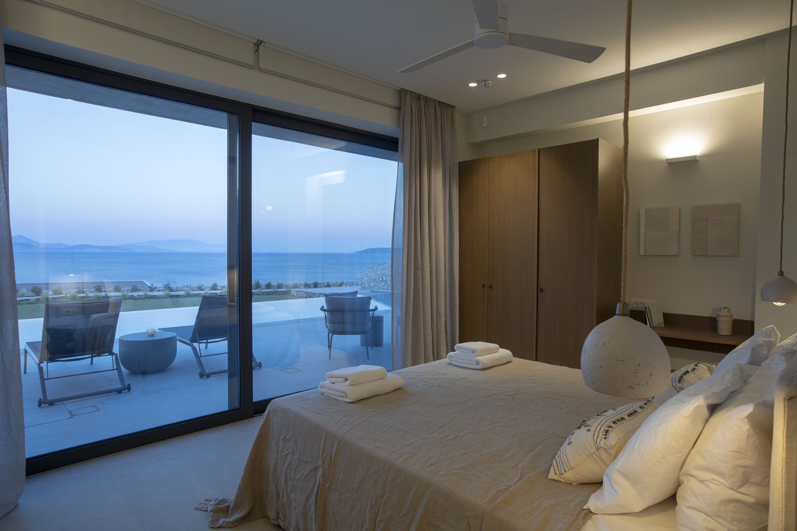 Sea-view suite at blue hour opening to the pool terrace